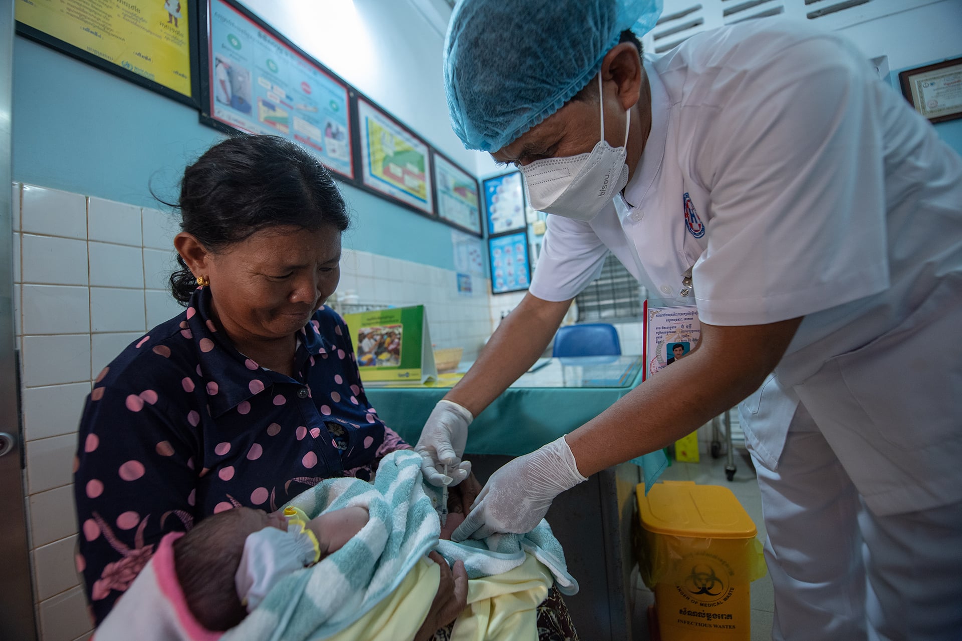 Mrs Sorn Earng holds her granddaughter while a health care worker performs a procedure on the baby at a health centre.