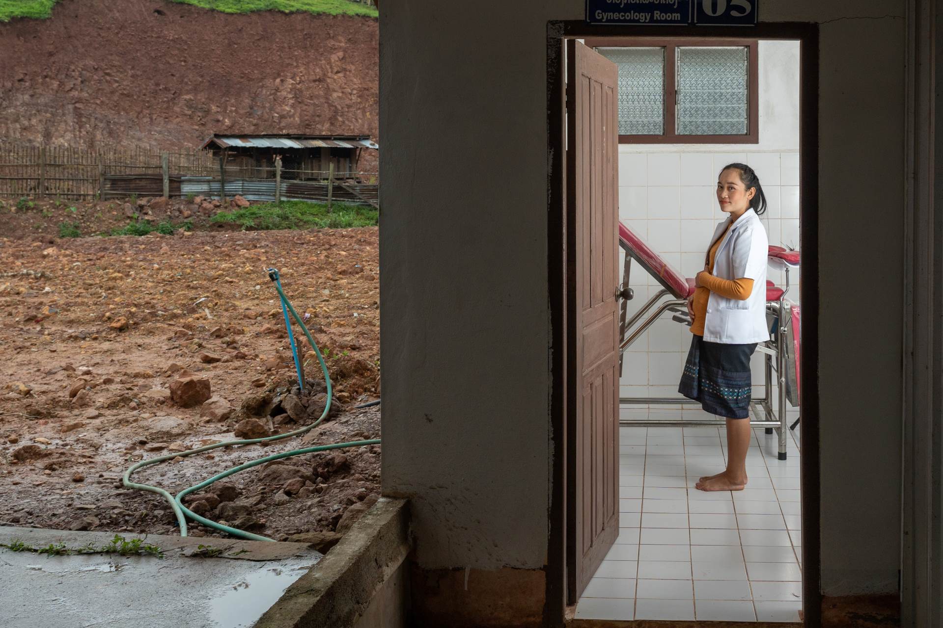 A pregnant nurse stands in a doorway at a clinic