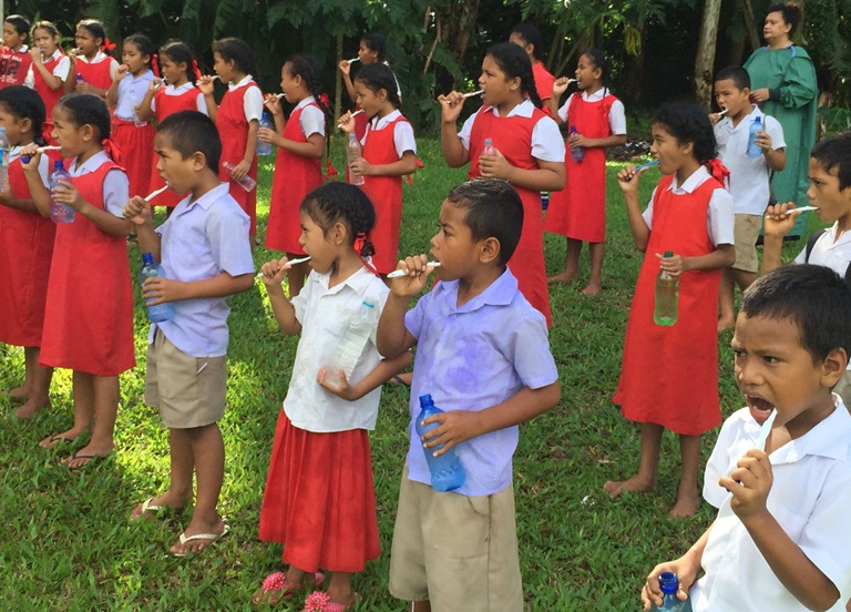 Children brush their teeth outside school in Tonga